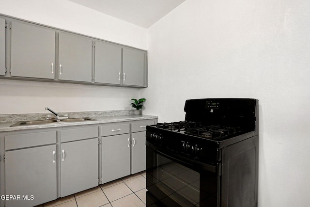 kitchen featuring black range with gas stovetop, gray cabinets, light tile patterned floors, and sink