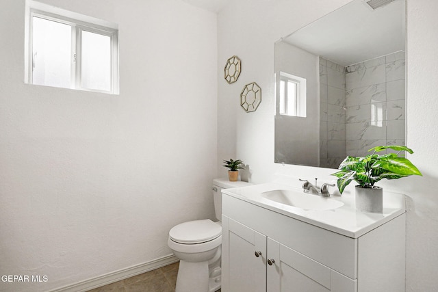 bathroom featuring tile patterned flooring, vanity, toilet, and tiled shower