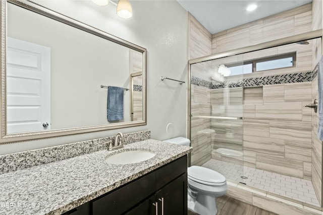 bathroom featuring hardwood / wood-style floors, vanity, toilet, and a shower with door