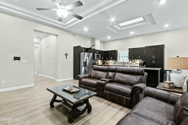 living room featuring ceiling fan, light hardwood / wood-style floors, and a raised ceiling