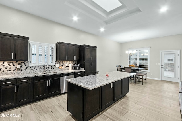 kitchen with dishwasher, sink, decorative backsplash, decorative light fixtures, and a kitchen island