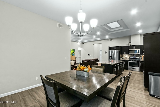 dining space featuring a notable chandelier, light hardwood / wood-style flooring, and a skylight