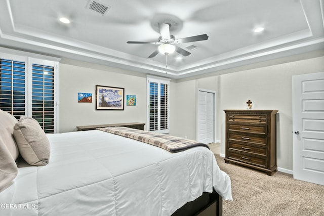 bedroom featuring ceiling fan, a raised ceiling, light carpet, and a closet