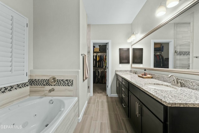 bathroom featuring tiled tub and vanity