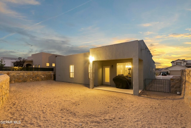 back house at dusk featuring a patio area