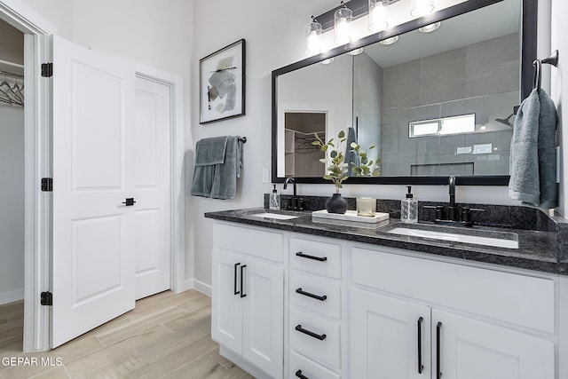 15224 Gauge Ct, El Paso, TX 79938 - bathroom featuring double vanity, a tile shower, baseboards, and wood finished floors