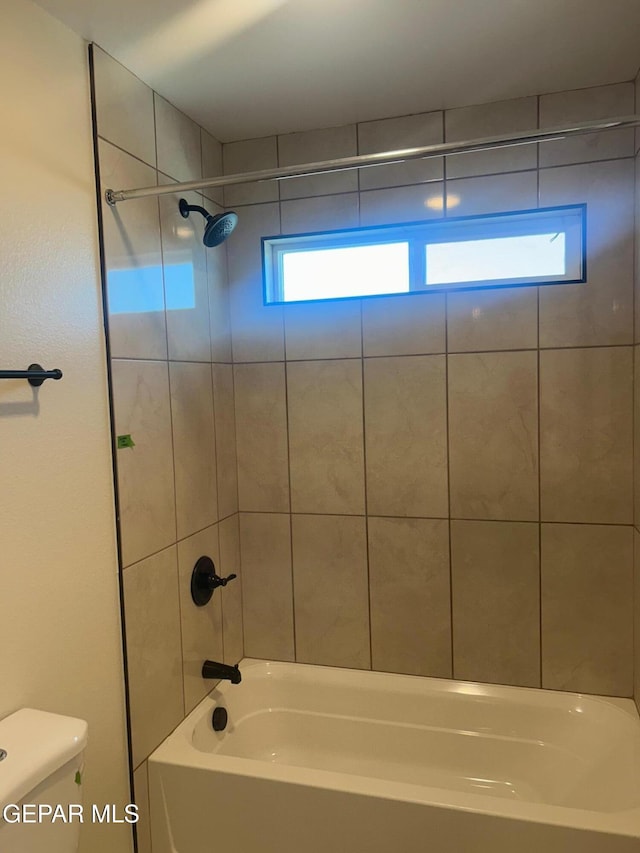 bathroom featuring toilet and tiled shower / bath