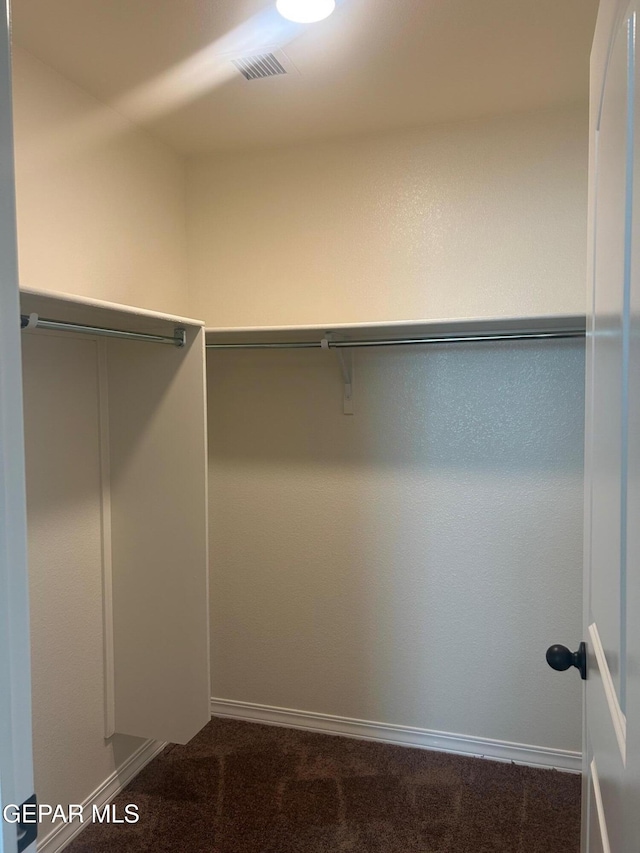 walk in closet with dark colored carpet