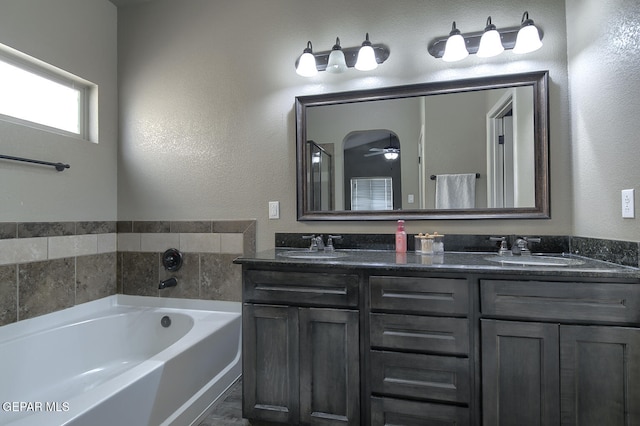 bathroom featuring vanity, ceiling fan, and a washtub