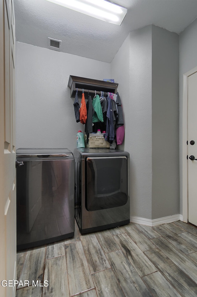 laundry room with separate washer and dryer, light hardwood / wood-style flooring, and a textured ceiling