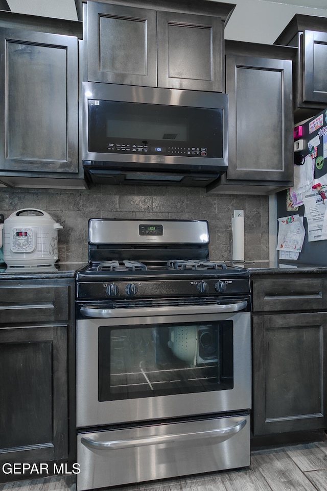 kitchen with decorative backsplash, stainless steel gas range oven, range hood, and light hardwood / wood-style flooring