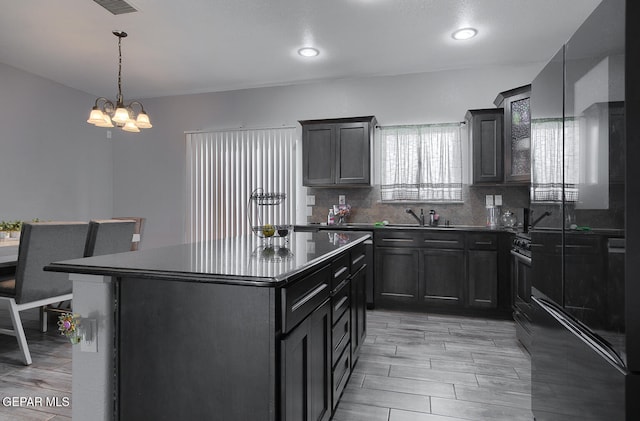 kitchen featuring tasteful backsplash, pendant lighting, a notable chandelier, light hardwood / wood-style floors, and a kitchen island