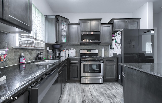 kitchen with dark stone counters, sink, decorative backsplash, light hardwood / wood-style floors, and stainless steel appliances