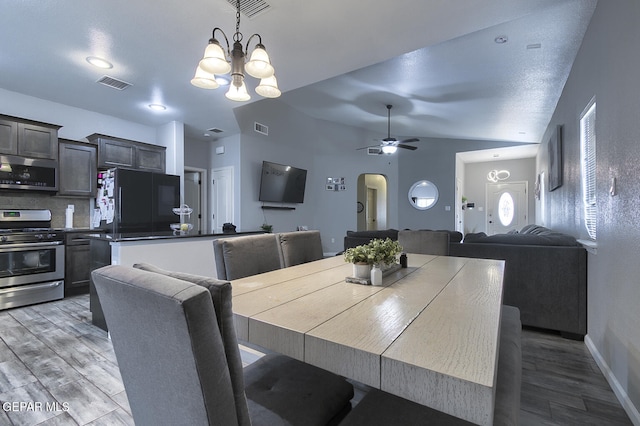 dining area featuring hardwood / wood-style floors, ceiling fan with notable chandelier, and vaulted ceiling