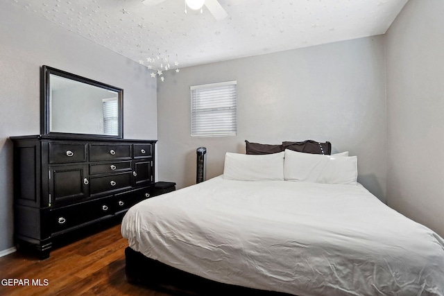 bedroom with dark hardwood / wood-style flooring and ceiling fan with notable chandelier