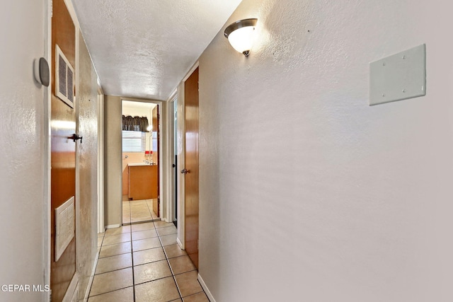 hallway with light tile patterned floors and a textured ceiling