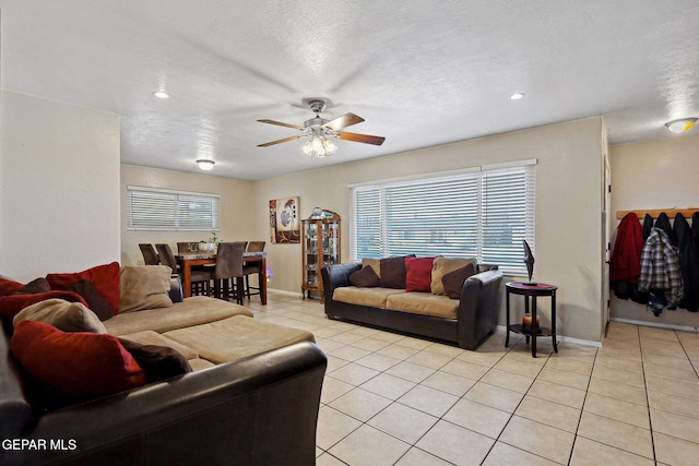 living room featuring a textured ceiling, ceiling fan, and light tile patterned flooring