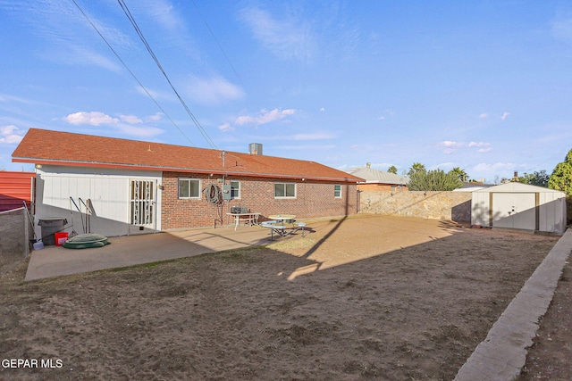 rear view of property with a storage shed and a patio