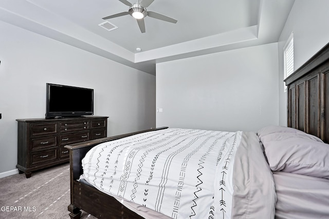 carpeted bedroom featuring ceiling fan and a tray ceiling