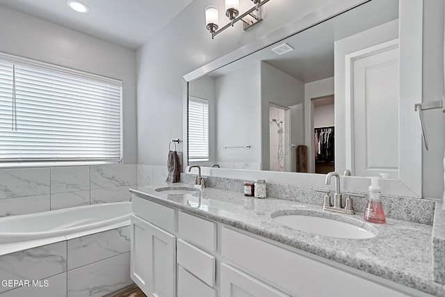 bathroom with vanity and a relaxing tiled tub