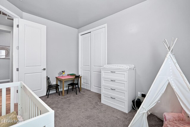 bedroom with light carpet, a closet, and a nursery area