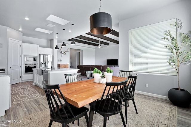 dining space featuring a skylight, ceiling fan, and light hardwood / wood-style flooring