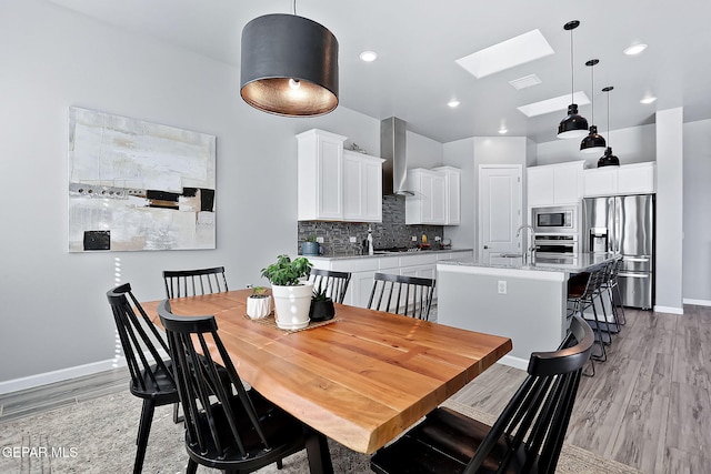 dining room featuring a skylight, light hardwood / wood-style flooring, and sink