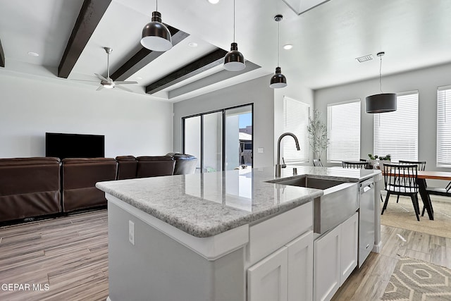 kitchen featuring a center island with sink, white cabinets, hanging light fixtures, ceiling fan, and a healthy amount of sunlight