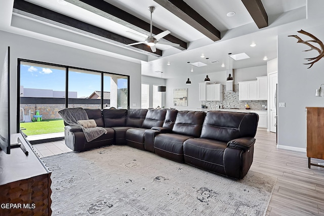 living room featuring ceiling fan, beam ceiling, and light wood-type flooring