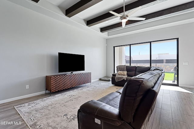 living room with beam ceiling, ceiling fan, and light wood-type flooring