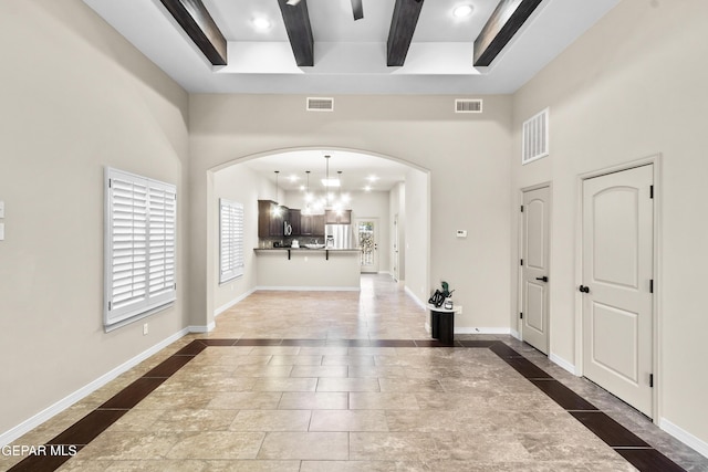 foyer with beamed ceiling and a high ceiling