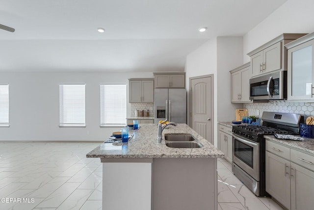 kitchen featuring decorative backsplash, appliances with stainless steel finishes, a kitchen island with sink, and sink