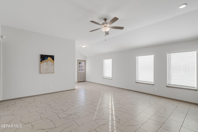 empty room featuring ceiling fan, a wealth of natural light, and vaulted ceiling