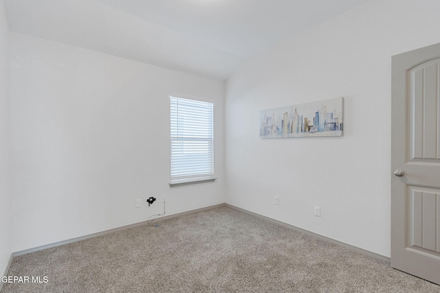 unfurnished room featuring light carpet and vaulted ceiling