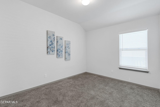 carpeted empty room with lofted ceiling