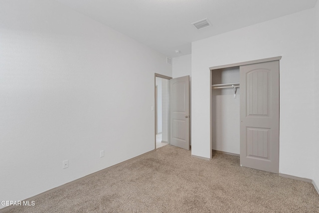 unfurnished bedroom with a closet and light colored carpet