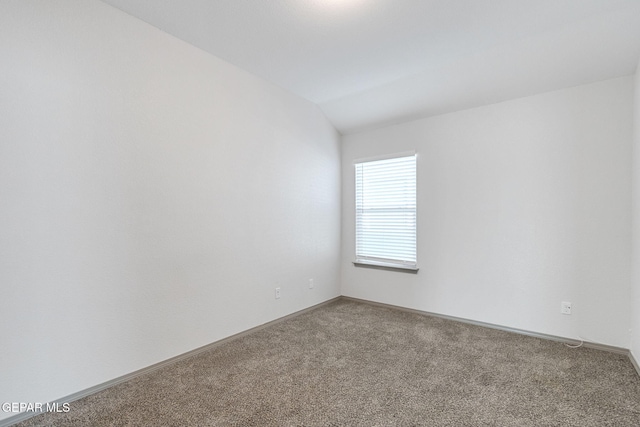 carpeted spare room with vaulted ceiling