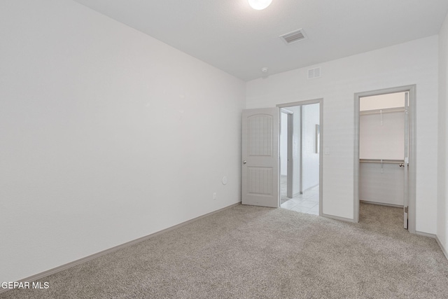 unfurnished bedroom featuring light carpet, a closet, and a spacious closet