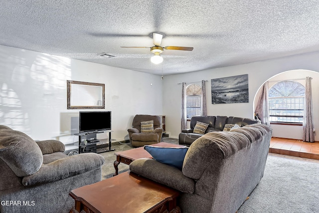 carpeted living room with ceiling fan and a textured ceiling