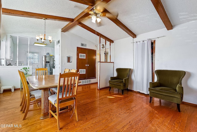 dining space with hardwood / wood-style floors, lofted ceiling with beams, a textured ceiling, and ceiling fan with notable chandelier