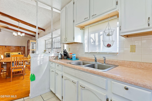 kitchen with pendant lighting, vaulted ceiling with beams, sink, and a wealth of natural light