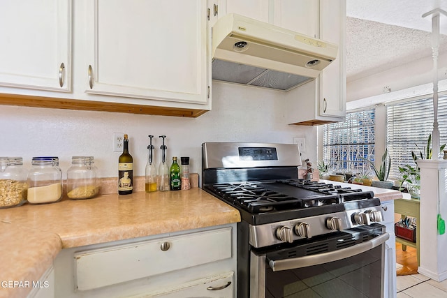 kitchen featuring light tile patterned floors, white cabinets, a textured ceiling, and stainless steel range with gas stovetop