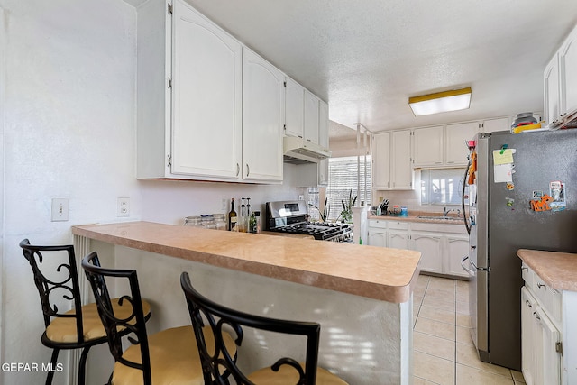 kitchen featuring a kitchen breakfast bar, kitchen peninsula, white cabinetry, and appliances with stainless steel finishes