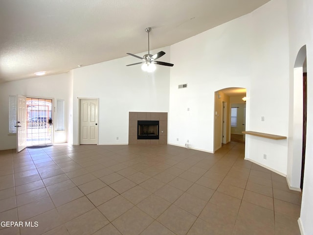 unfurnished living room featuring tile patterned flooring, high vaulted ceiling, ceiling fan, and a tiled fireplace