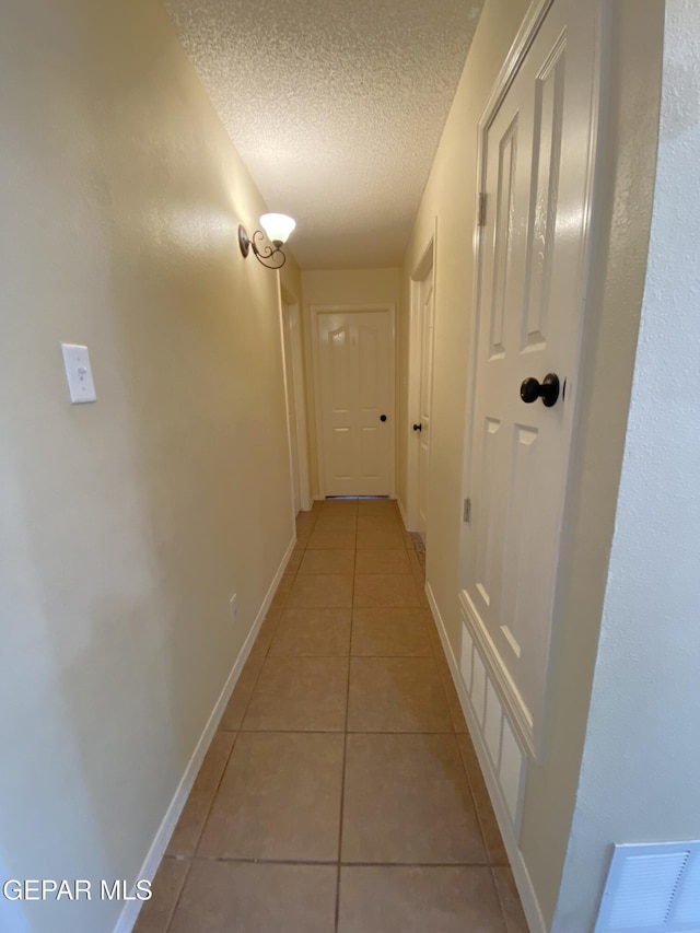 hallway with light tile patterned floors and a textured ceiling