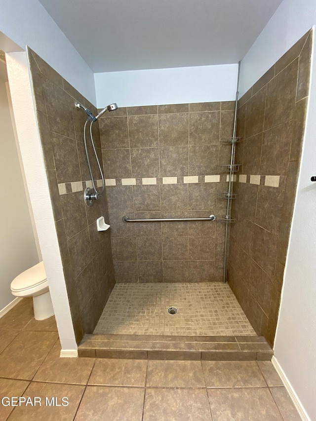 bathroom featuring tile patterned floors, toilet, and tiled shower