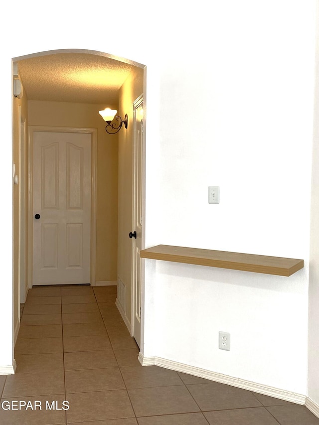 corridor with a textured ceiling and tile patterned floors