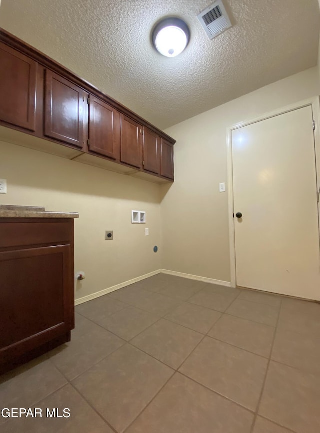 washroom featuring cabinets, hookup for an electric dryer, hookup for a washing machine, a textured ceiling, and light tile patterned flooring