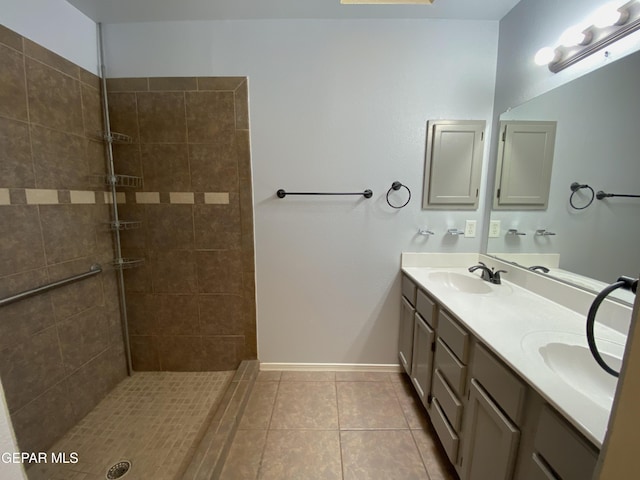 bathroom featuring tile patterned flooring, a tile shower, and vanity