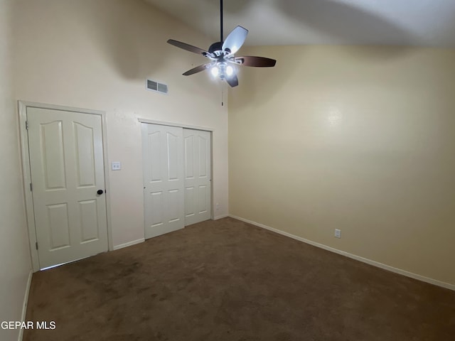 unfurnished bedroom with ceiling fan, dark carpet, and high vaulted ceiling